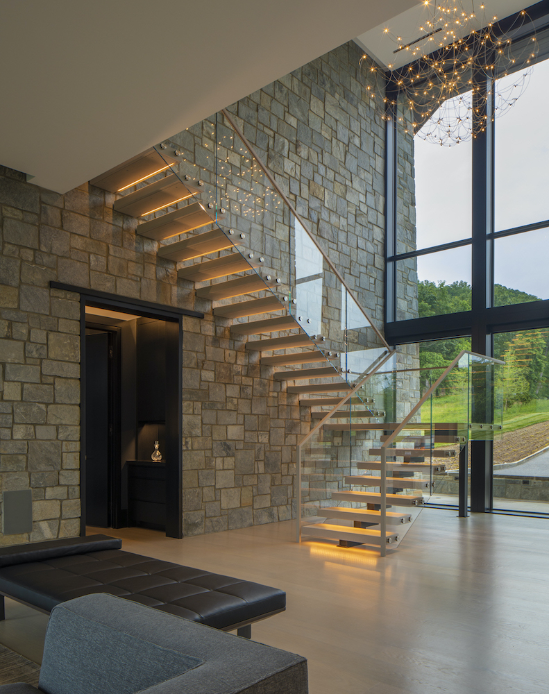 floating staircase white oak underlit treads stone wall steel glass rail